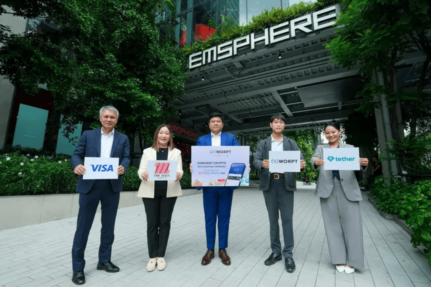 ผู้แทนจาก Visa, The Mall Group, WORPT และ Tether ถือป้ายโลโก้ร่วมกันหน้าศูนย์การค้า EMSPHERE ในการเปิดให้บริการแอปพลิเคชัน WORPT